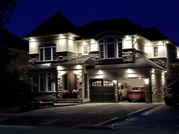 Stone-front home with potlights along the roofline and porch
