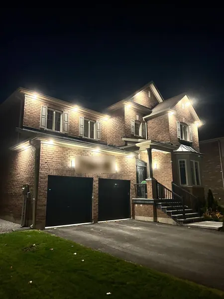 Red-brick home with bright soffit potlights at night