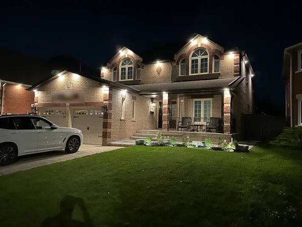 Brick home with potlights over the porch, gables and garage