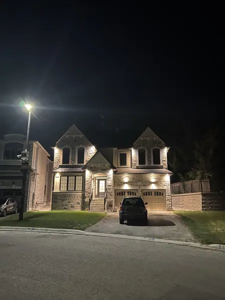 Stone home with exterior potlights on a quiet street at night