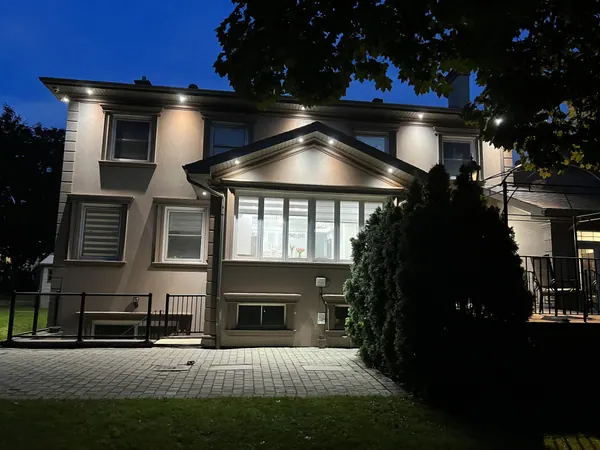 Back of a home lit by soffit potlights at dusk