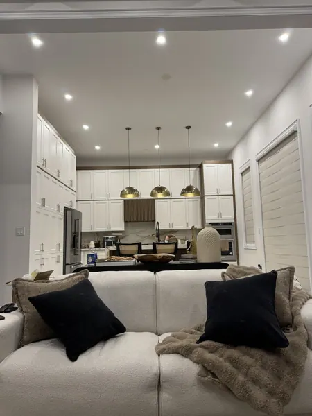 Open-concept living room and kitchen with potlights and gold pendants